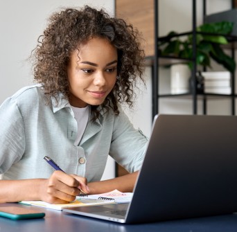 Girl taking notes at laptop