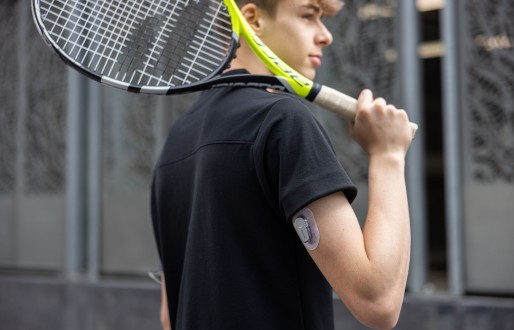 Een tiener met diabetes type 1 speelt tennis, met zijn CGM Dexcom G6-sensor