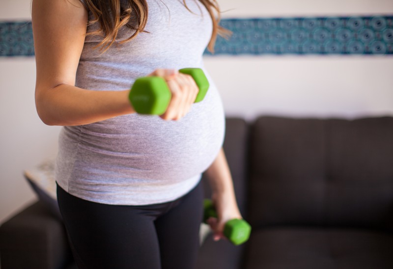 Pregnant person holding small weights for exercise