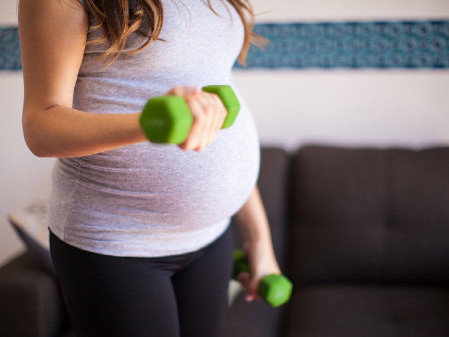 Pregnant person holding small weights for exercise